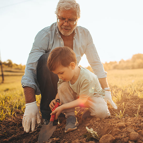 A Grandfather Helps His Grandson Plant A Garden As Part of Ripple Impact’s Support of Our Natural World