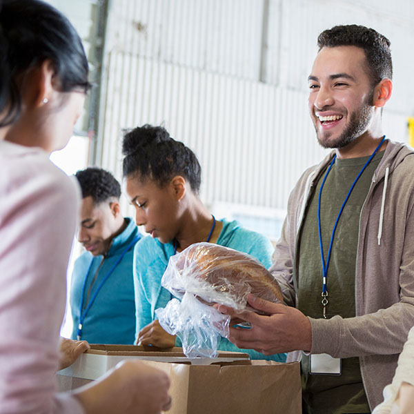 A man gives a homeless woman food at a food bank as part of RIpple Impact’s homelessness-houselessness giving circle