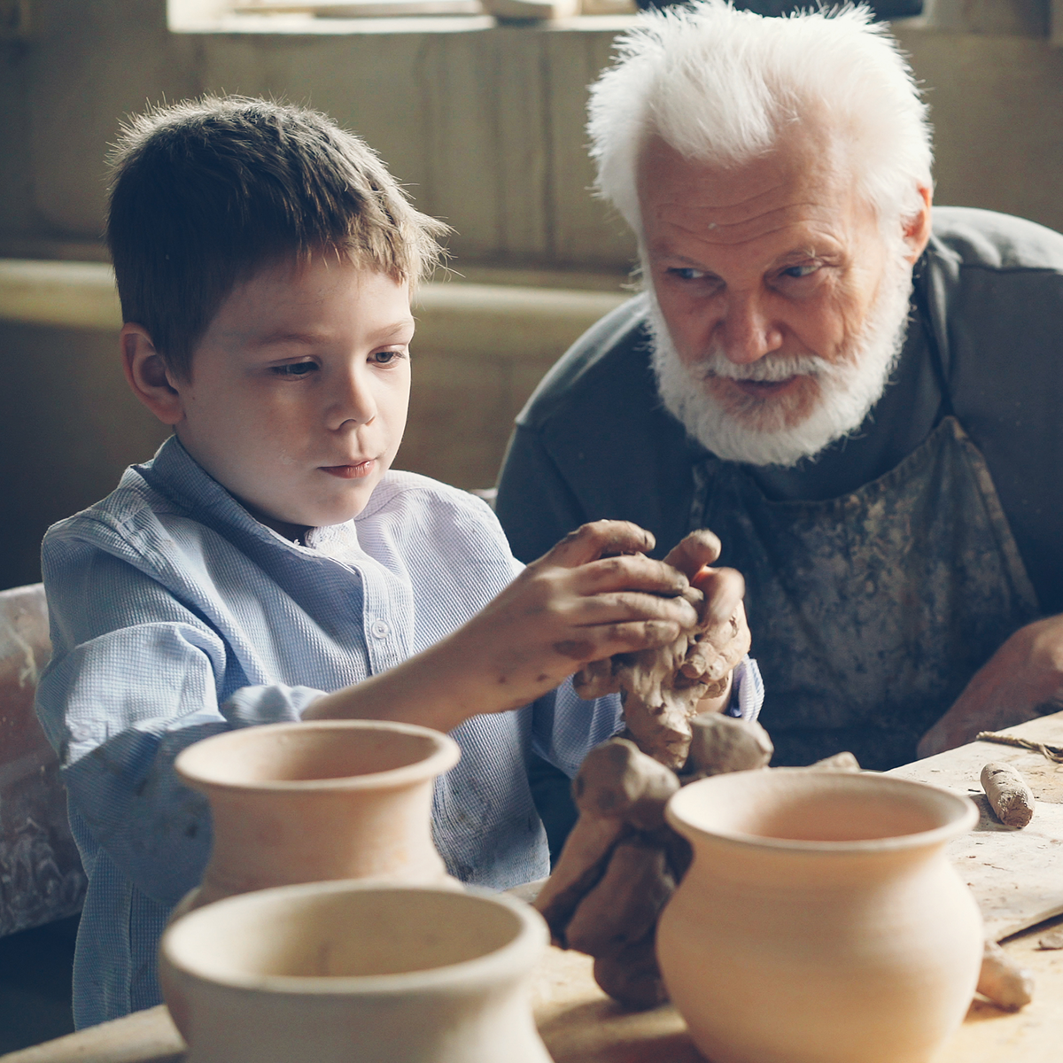 Grandfather teaching grandson how to do pottery