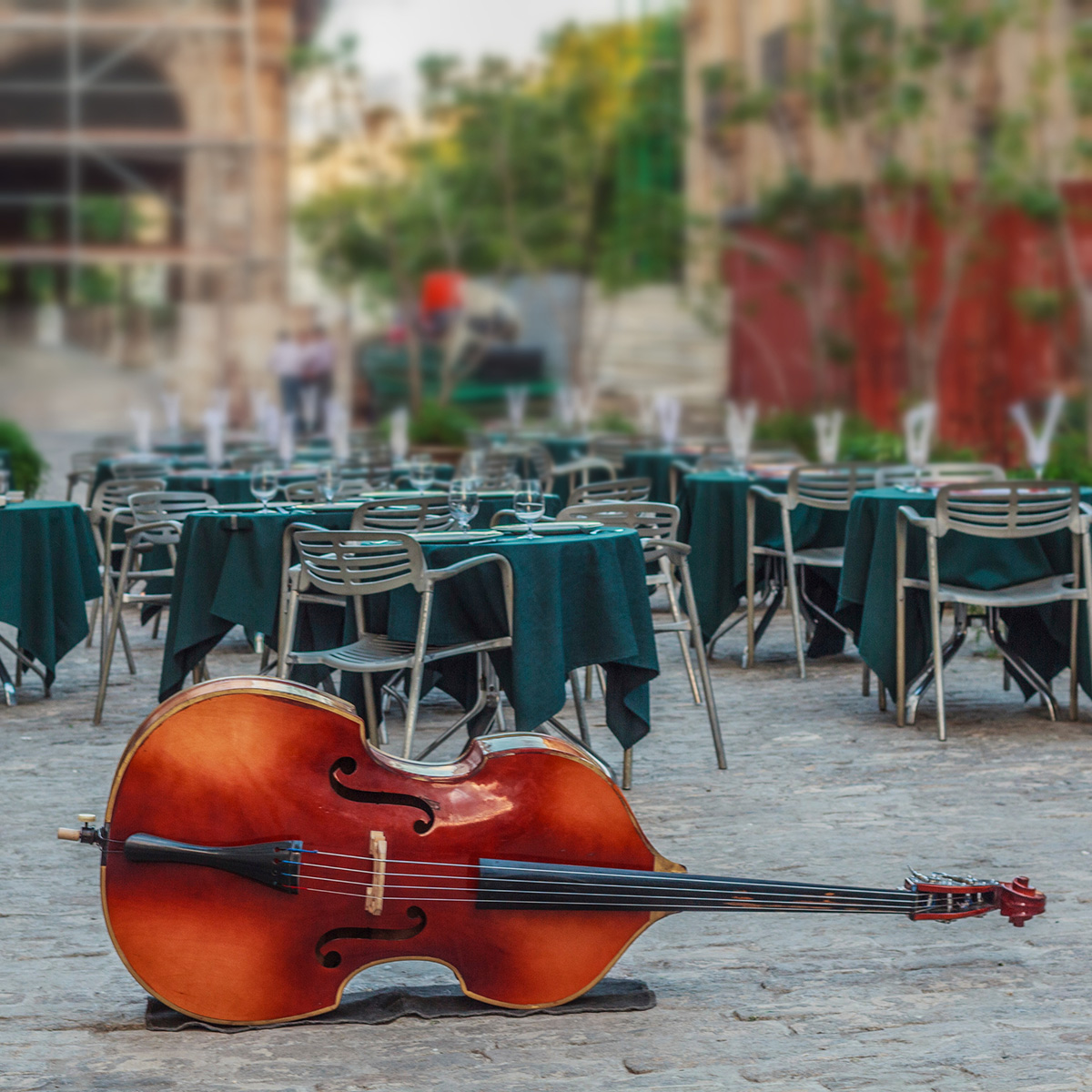 a cello sitting in a cobblestone square